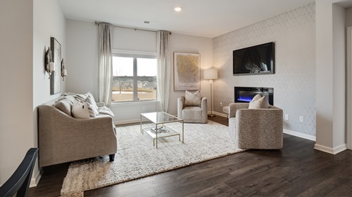 cali plan model in twin lakes community living room with an electric fireplace included and a large double window overlooking the backyard