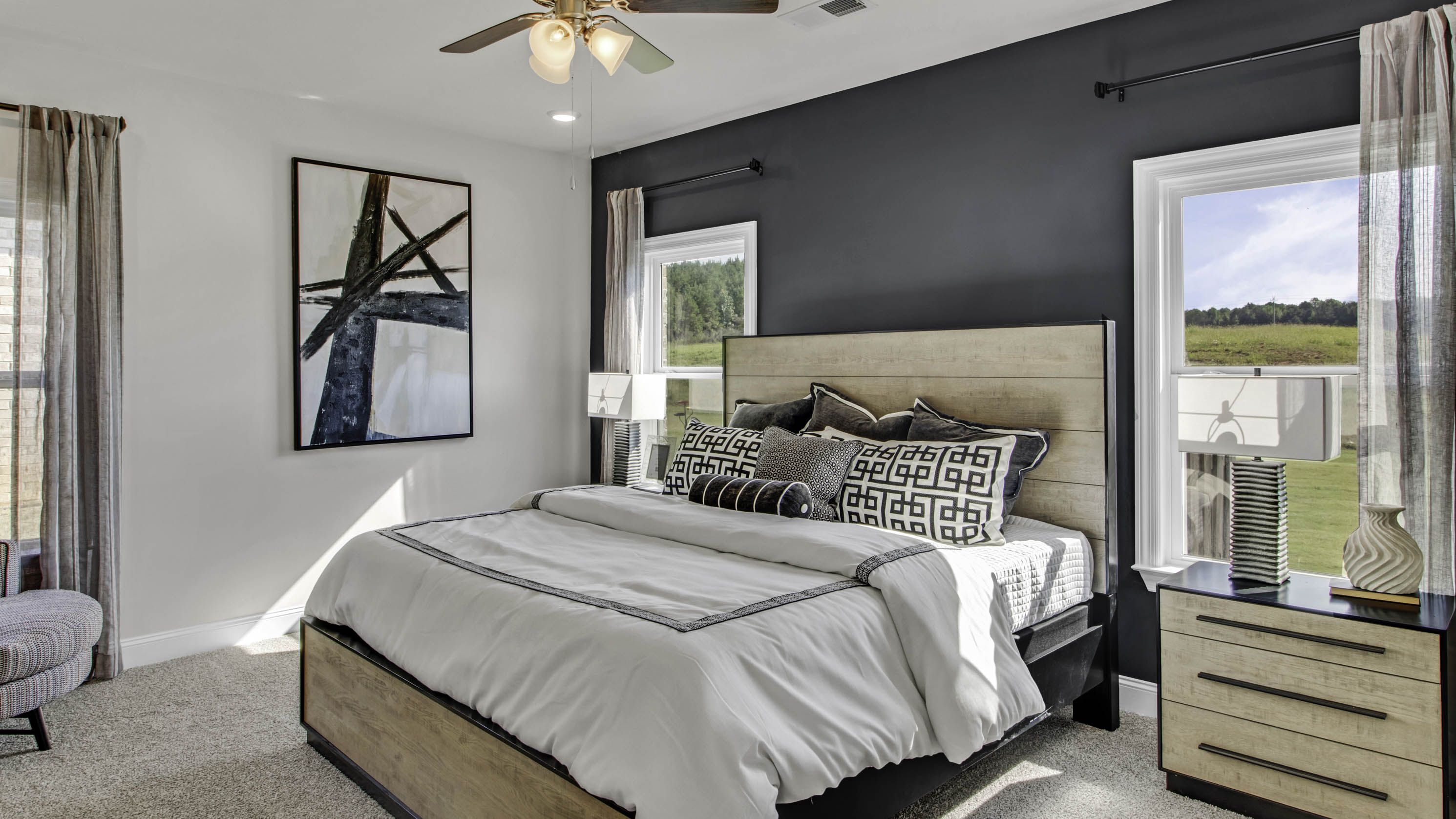 Spacious primary bedroom with two tall windows overlooking the backyard