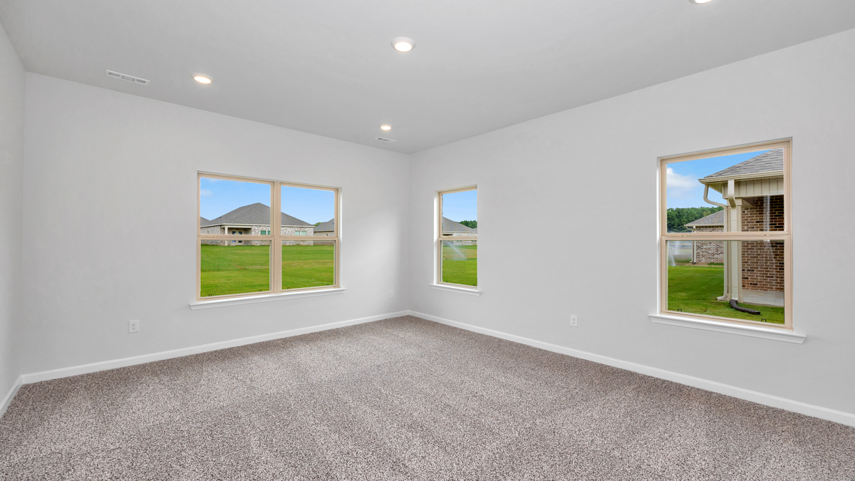 Spacious primary bedroom with windows for natural light