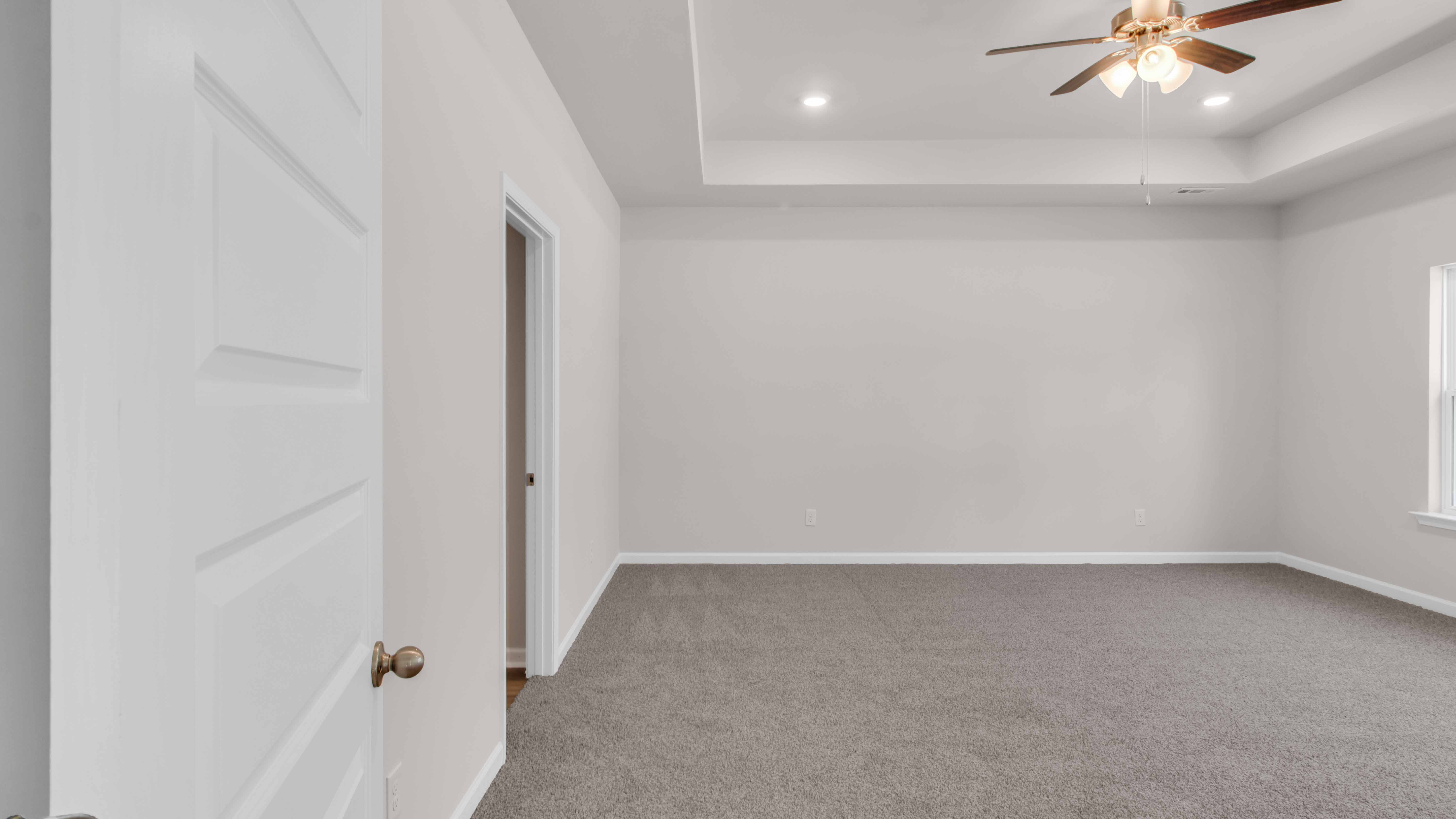 Spacious primary bedroom with neutral paint and carpet flooring