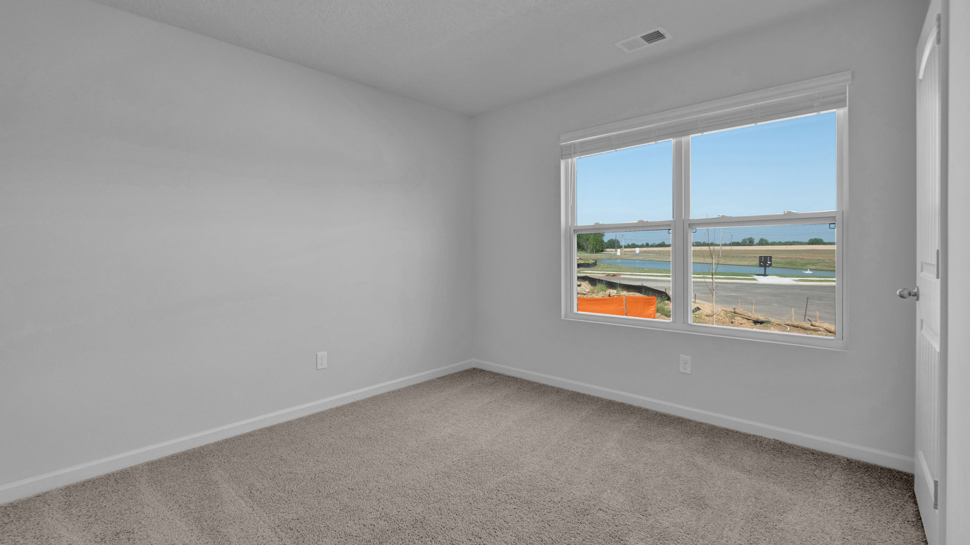 Second bedroom at the front of the home with a large double window overlooking the front yard