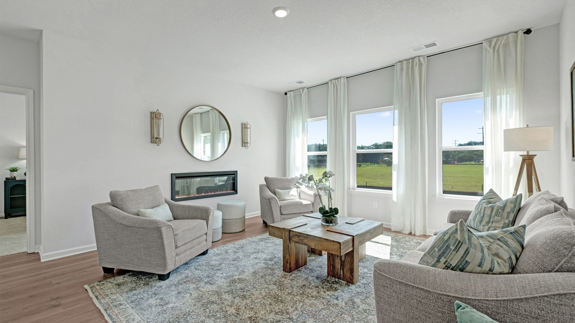 Living room with three tall windows overlooking the backyard