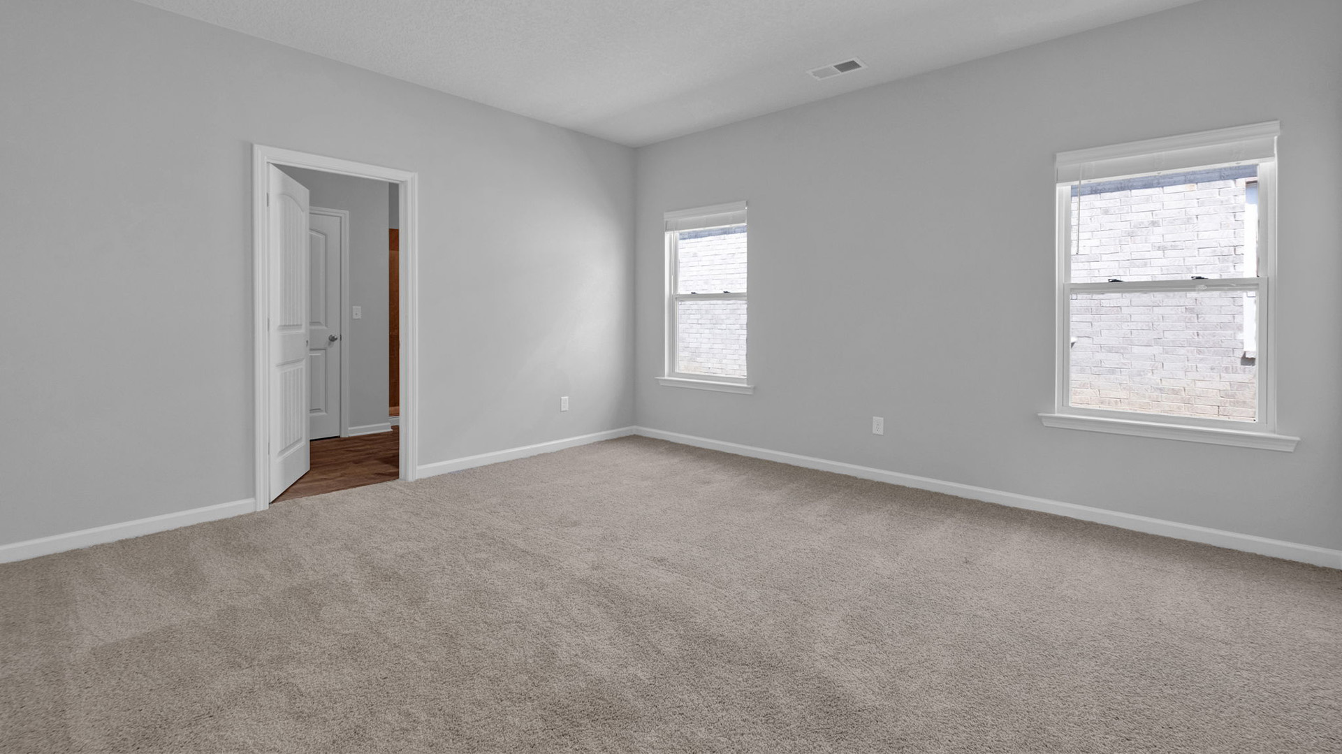 Spacious primary bedroom with two windows for natural light