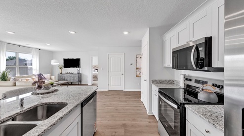 Kitchen area with vinyl flooring and neutral cabinets