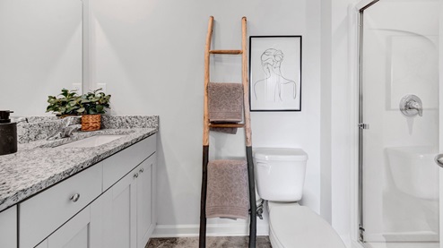 En suite primary bathroom with a granite countertop double vanity