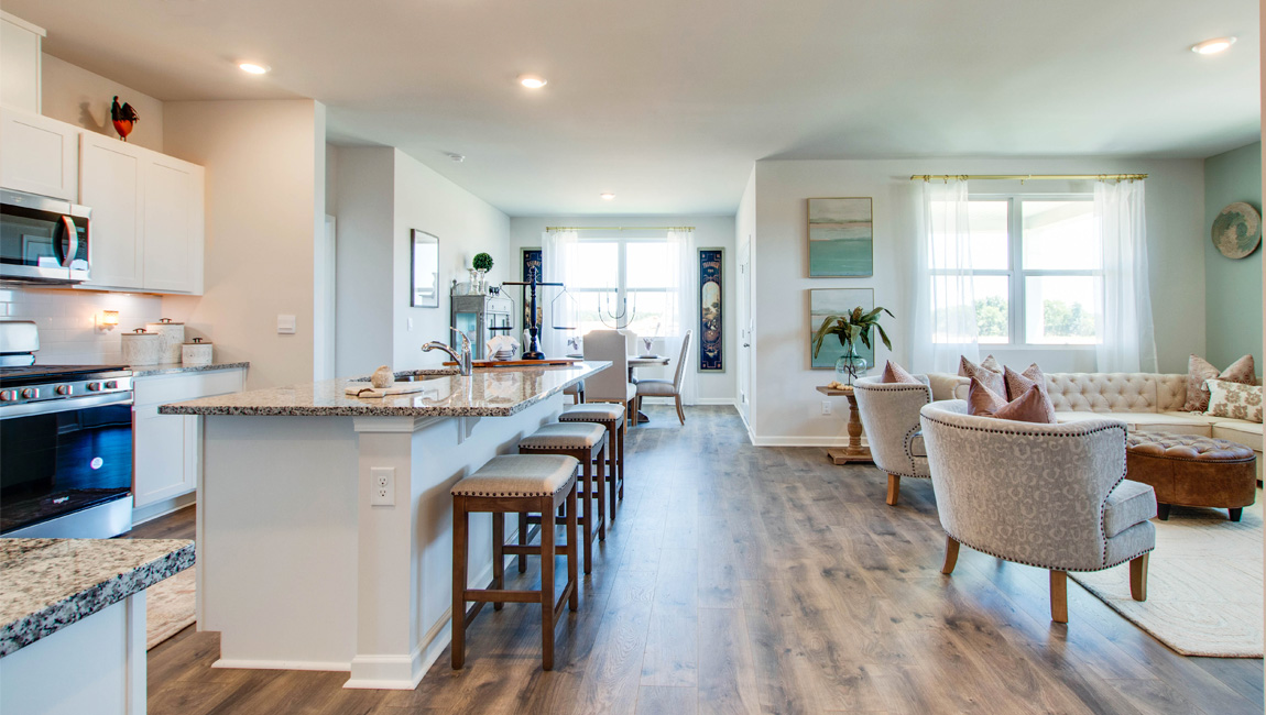 bristol plan open-concept living with kitchen overlooking the living room and revwood laminate flooring throughout main areas in the orchard community