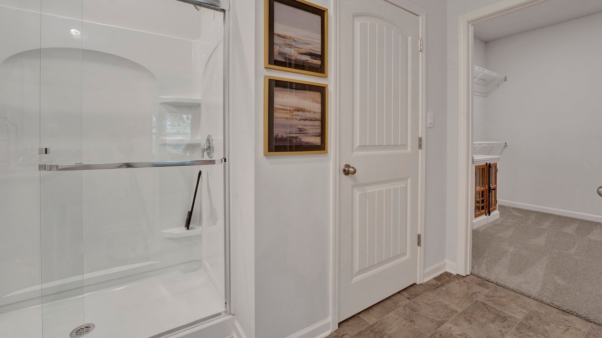 cameron plan primary bathroom with vinyl flooring, walk-in shower with glass enclosure, and separate linen closet located jout outside the walk-in primary closet in the orchard community