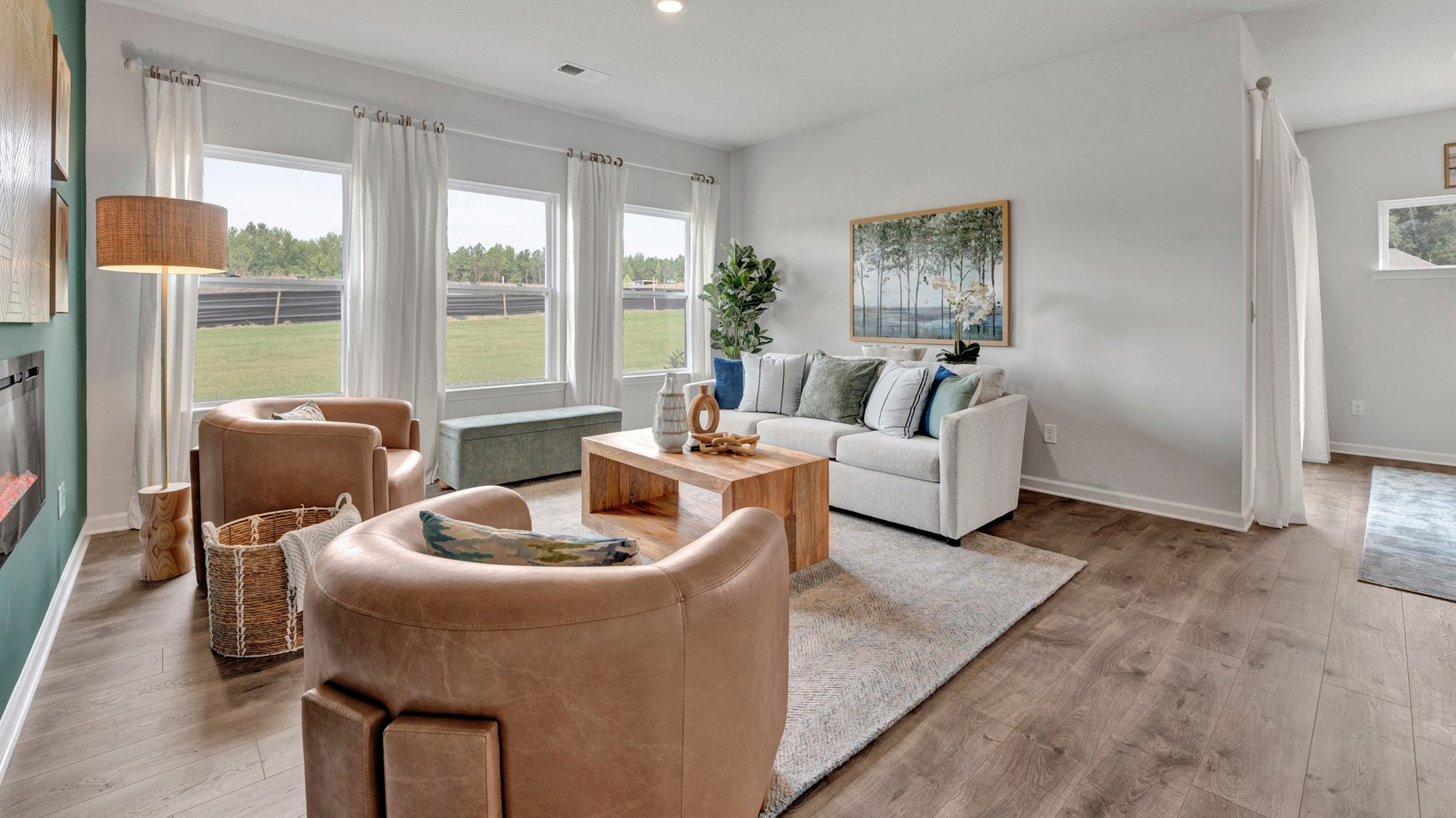 dover plan living room with 3 large windows looking out to the back yard, revwood laminate flooring, and plenty of room for several pieces of furniture in the orchard community