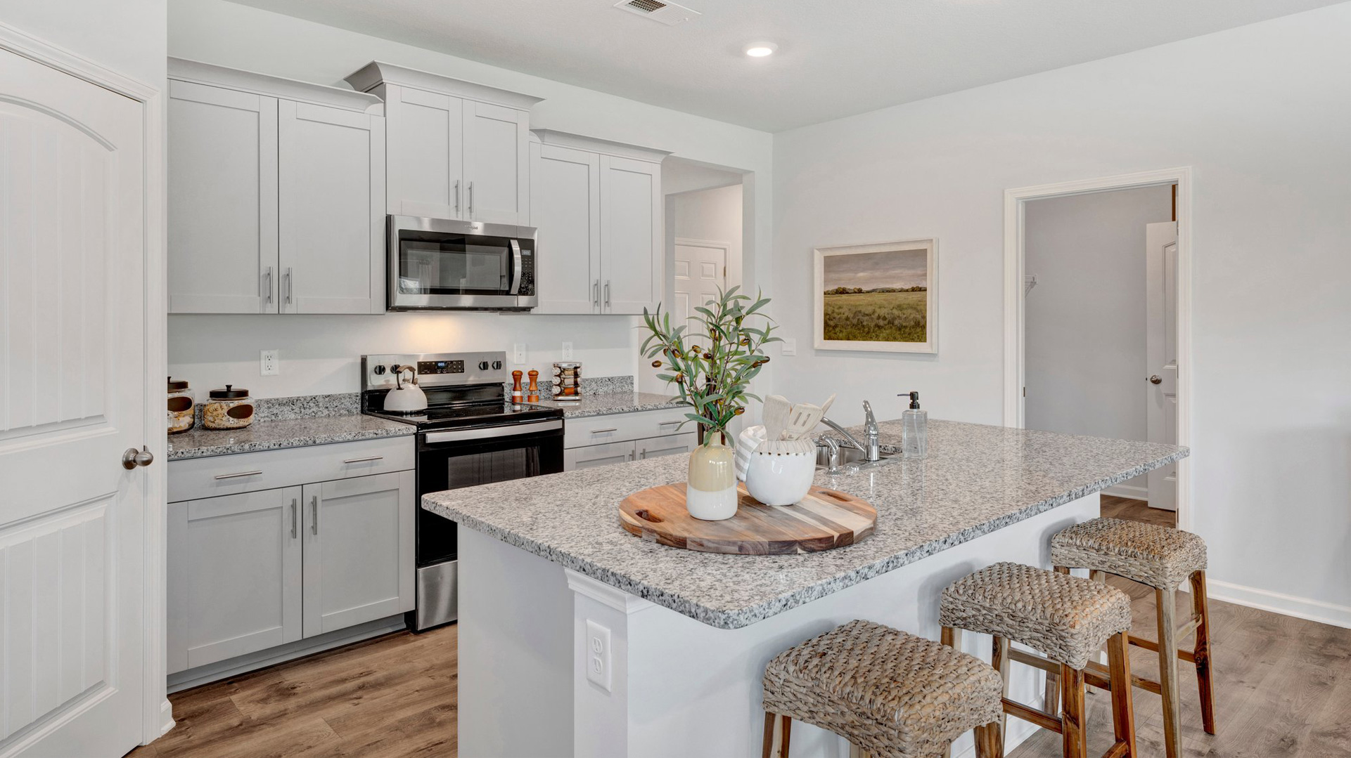 dover plan kitchen with bar seating at the island, granite countertops, tall cabinets with crown and hardware, and stainless steel appliances included in the orchard community