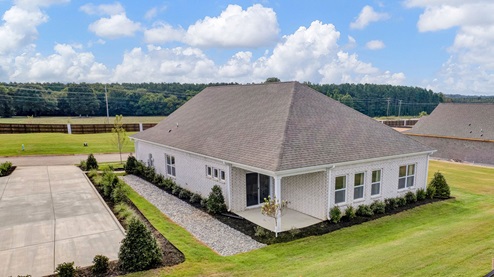 exterior view of the home showcasing the abundance of windows near the back of the home and a covered patio