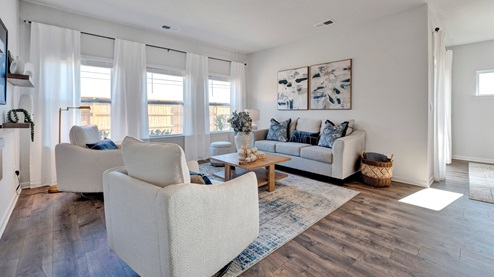 Spacious living room with a backwall of tall windows overlooking the backyard