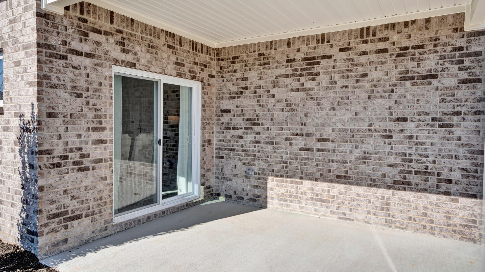 Backyard with concrete patio area offering room for seating, grill setup, and a transition from indoor to outdoor living