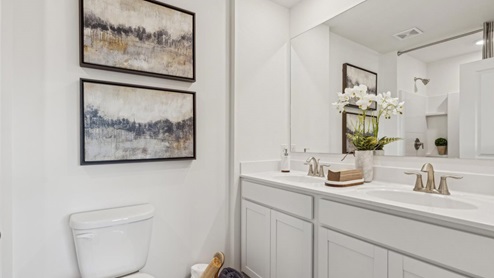 En suite primary bathroom with a single vanity and two sinks and a walk in shower