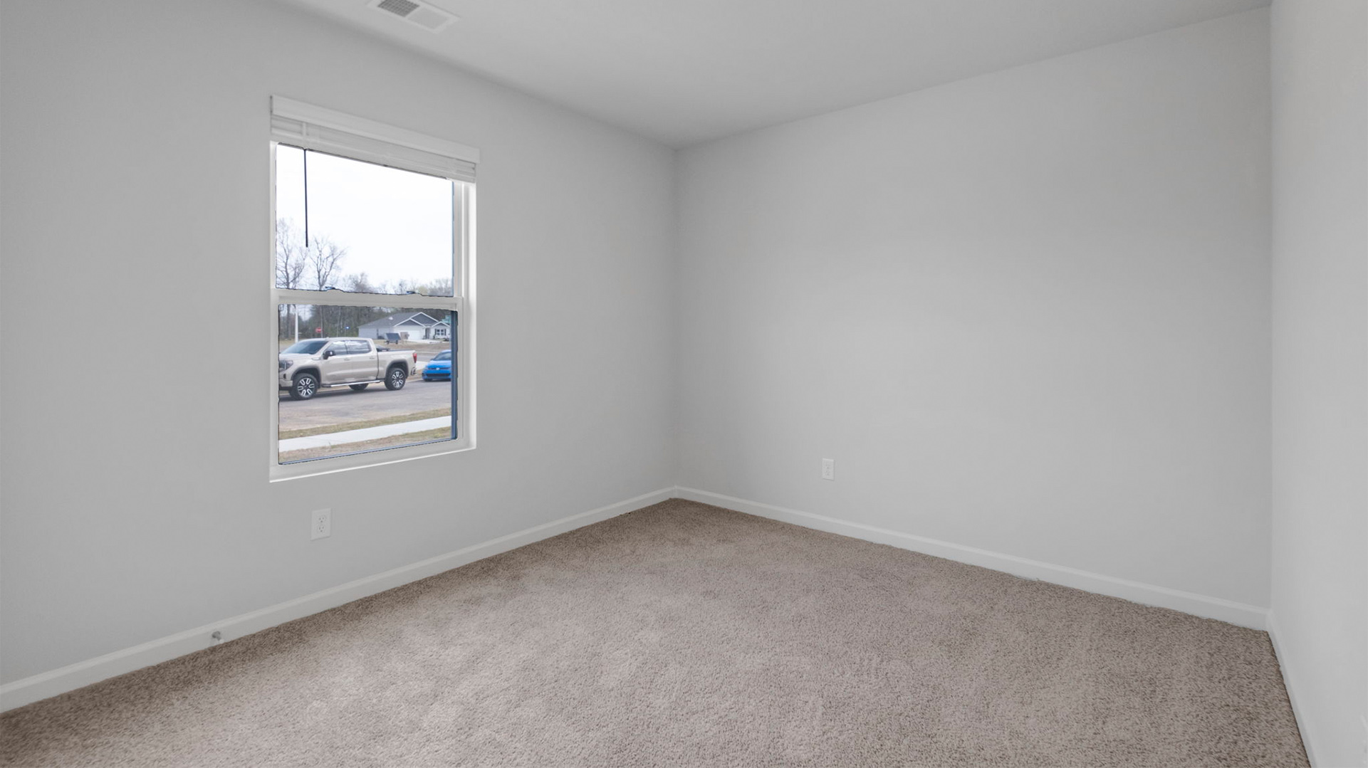 Second bedroom at the front of the home with carpet flooring