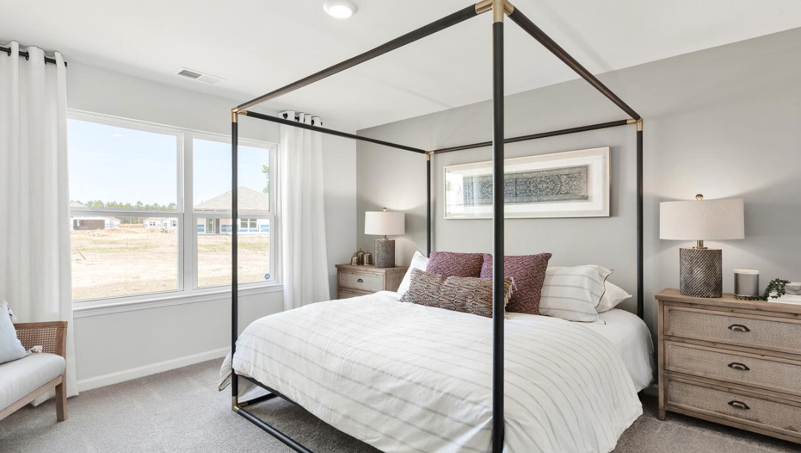 Primary bedroom staged with a canopy king size bed