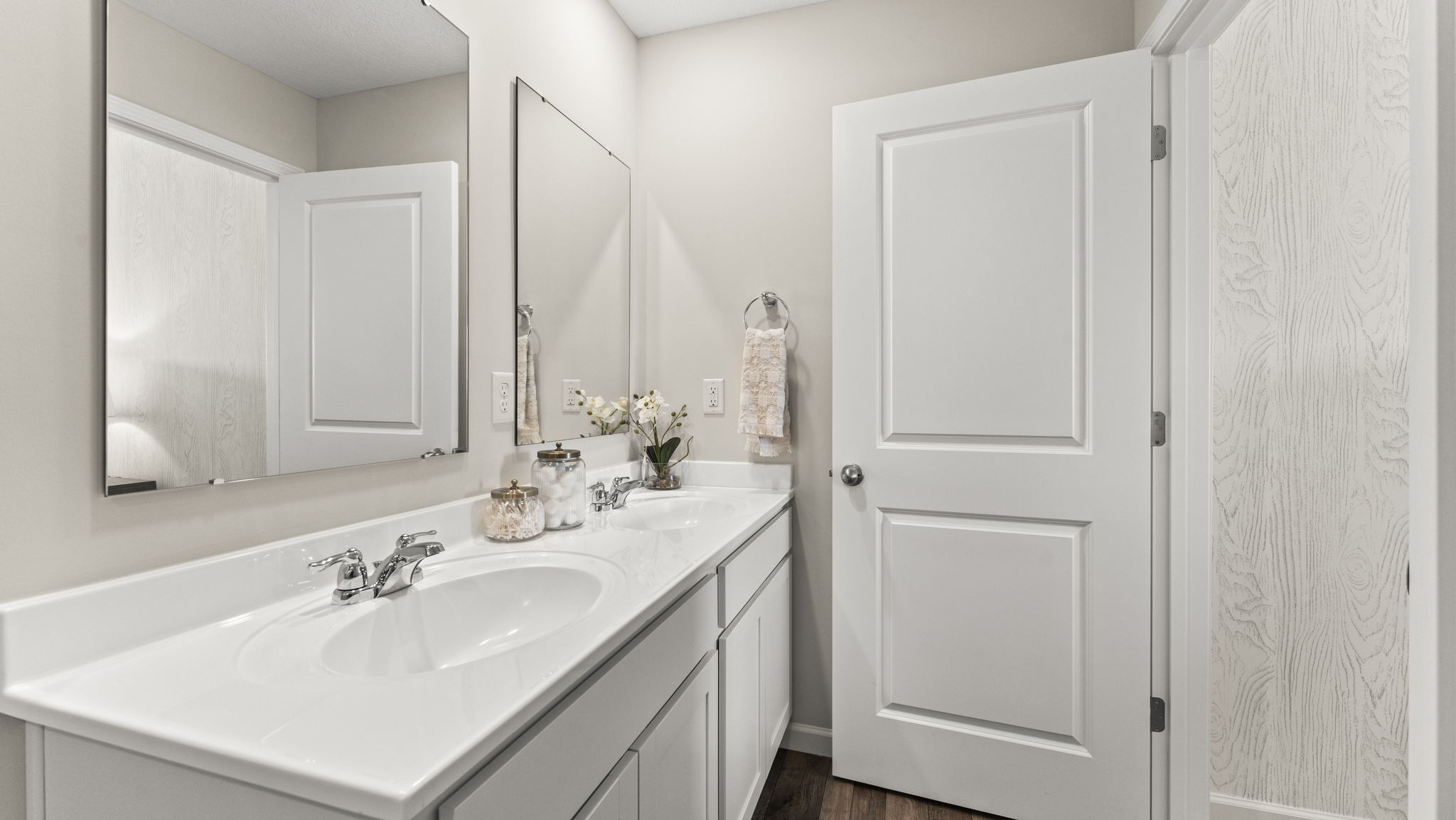 En suite primary bathroom with a large mirror overlooking the dual vanity