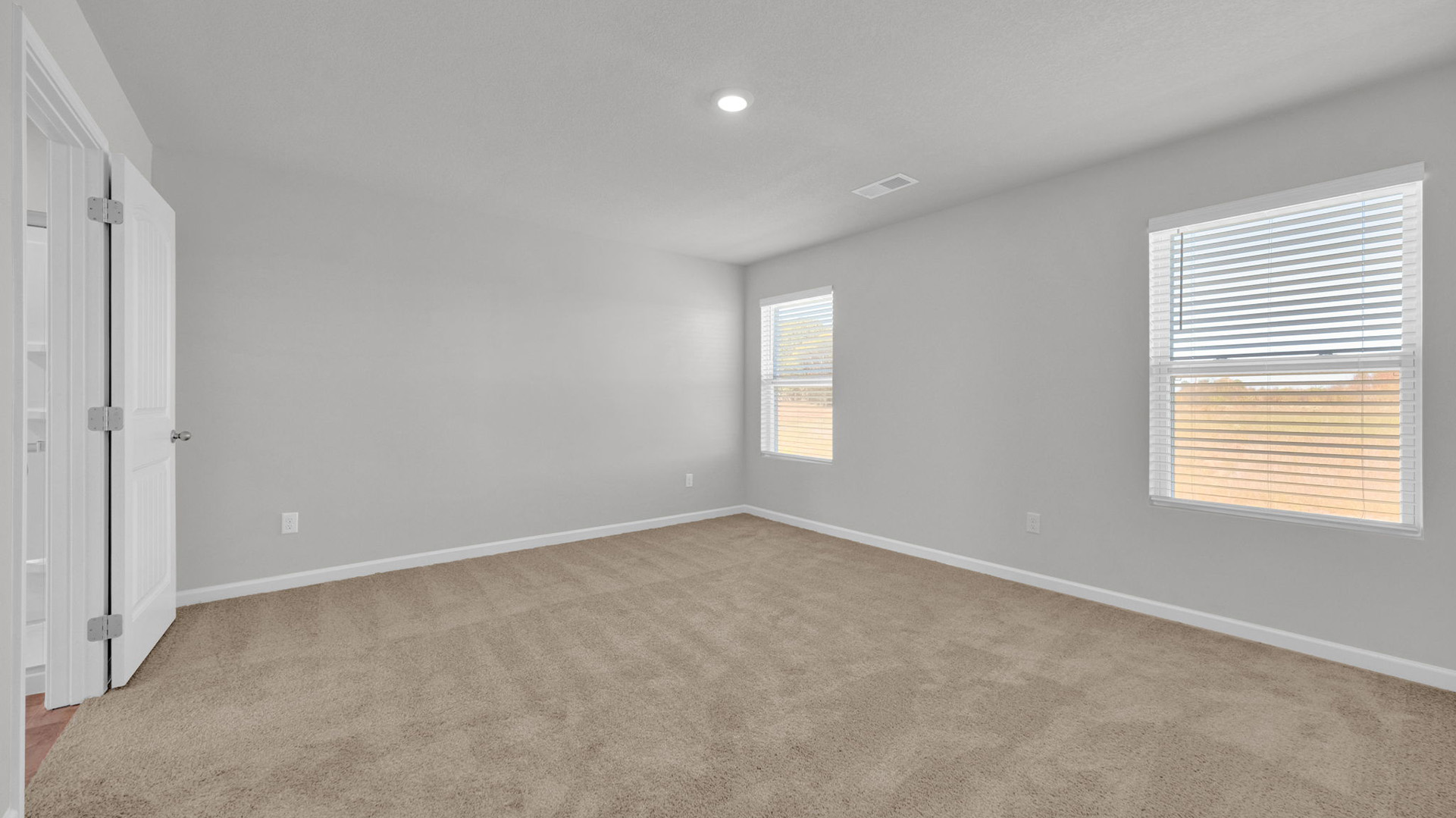 Primary bedroom with two tall window overlooking the backyard