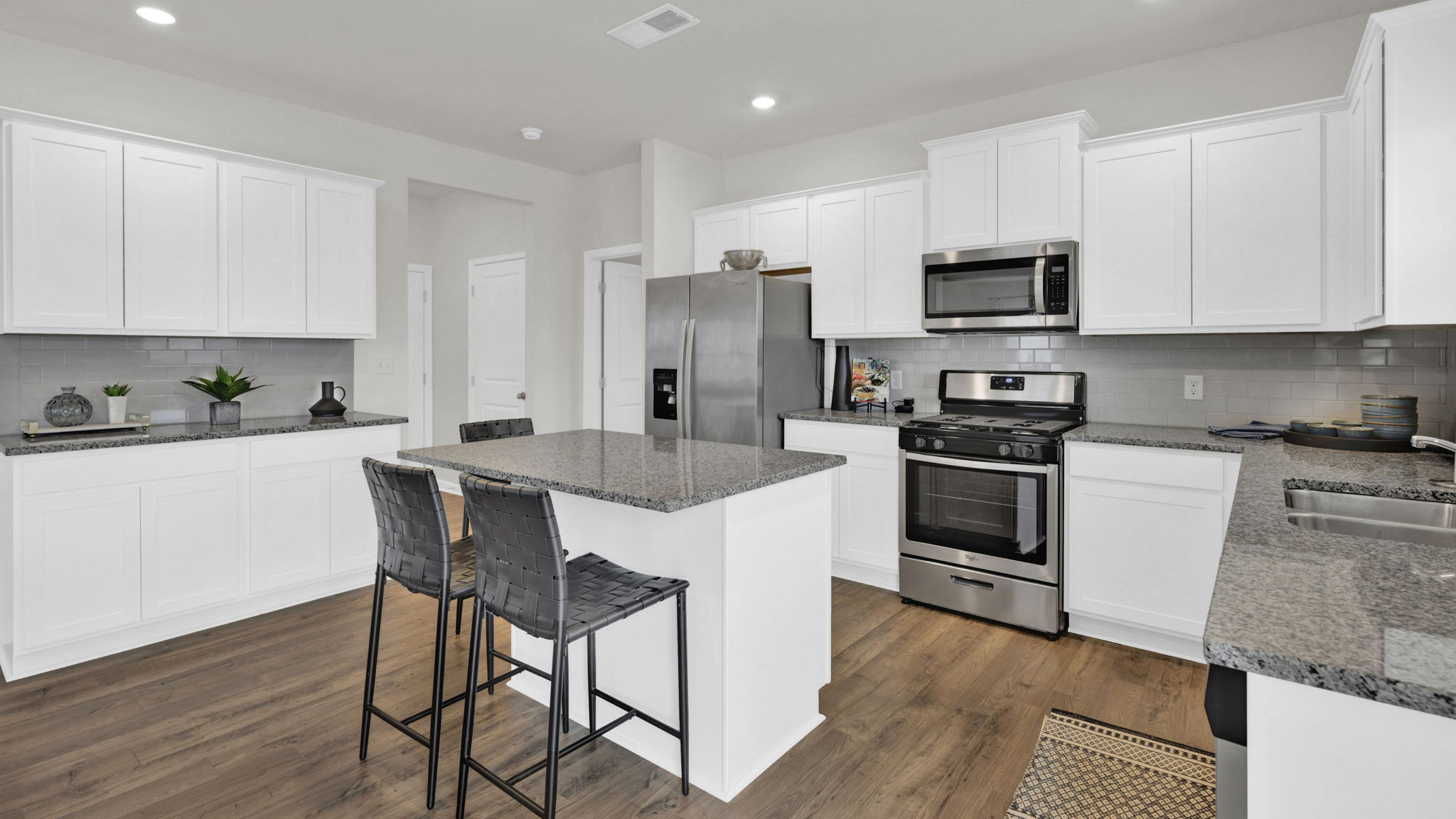 the kitchen has an island and white cabinets