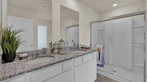 Primary bathroom with double vanity and a glass door shower