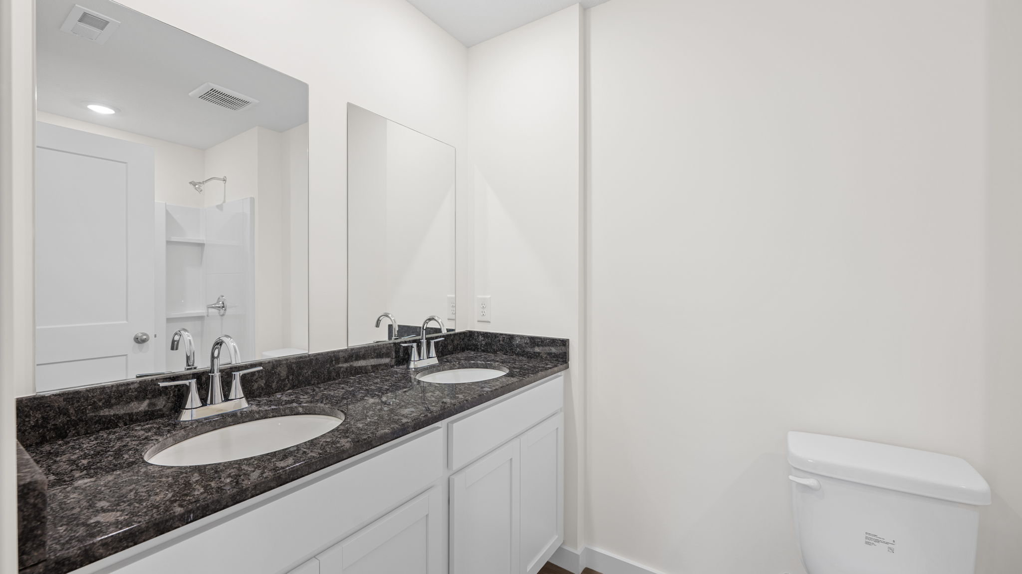 primary bathroom with dual sinks and mirror