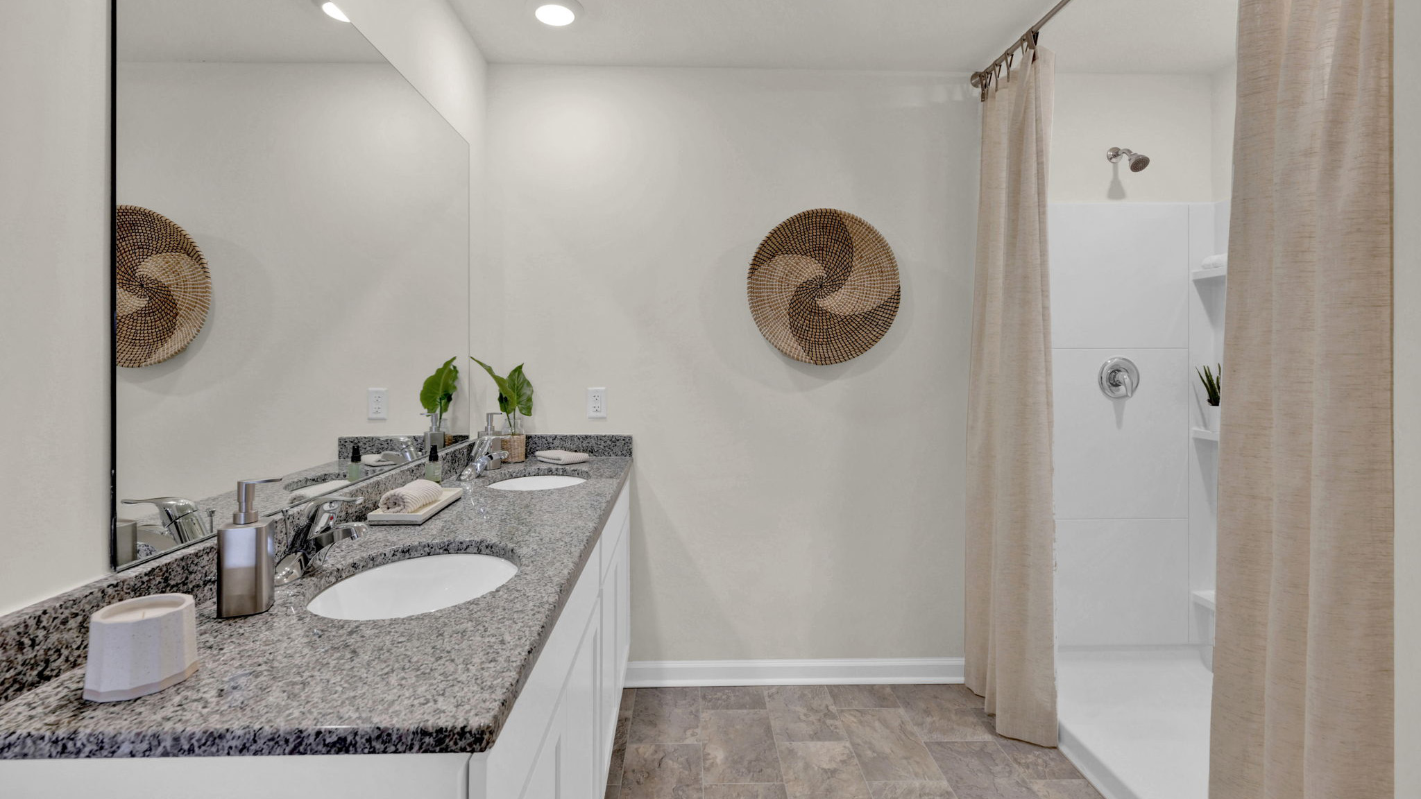 bathroom with dual sinks and standup shower