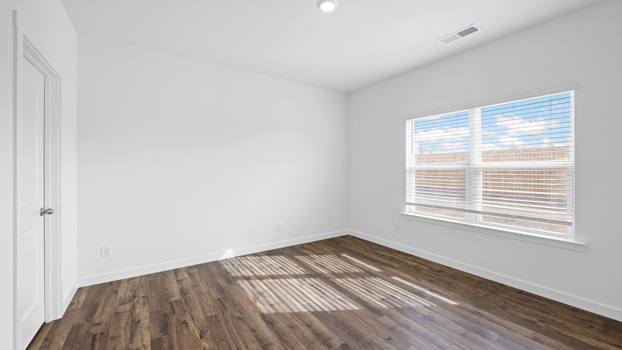 bedroom with dark brown flooring and large window
