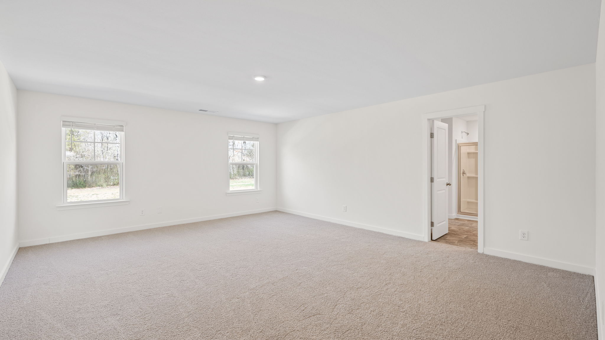 primary bedroom with two windows and open door