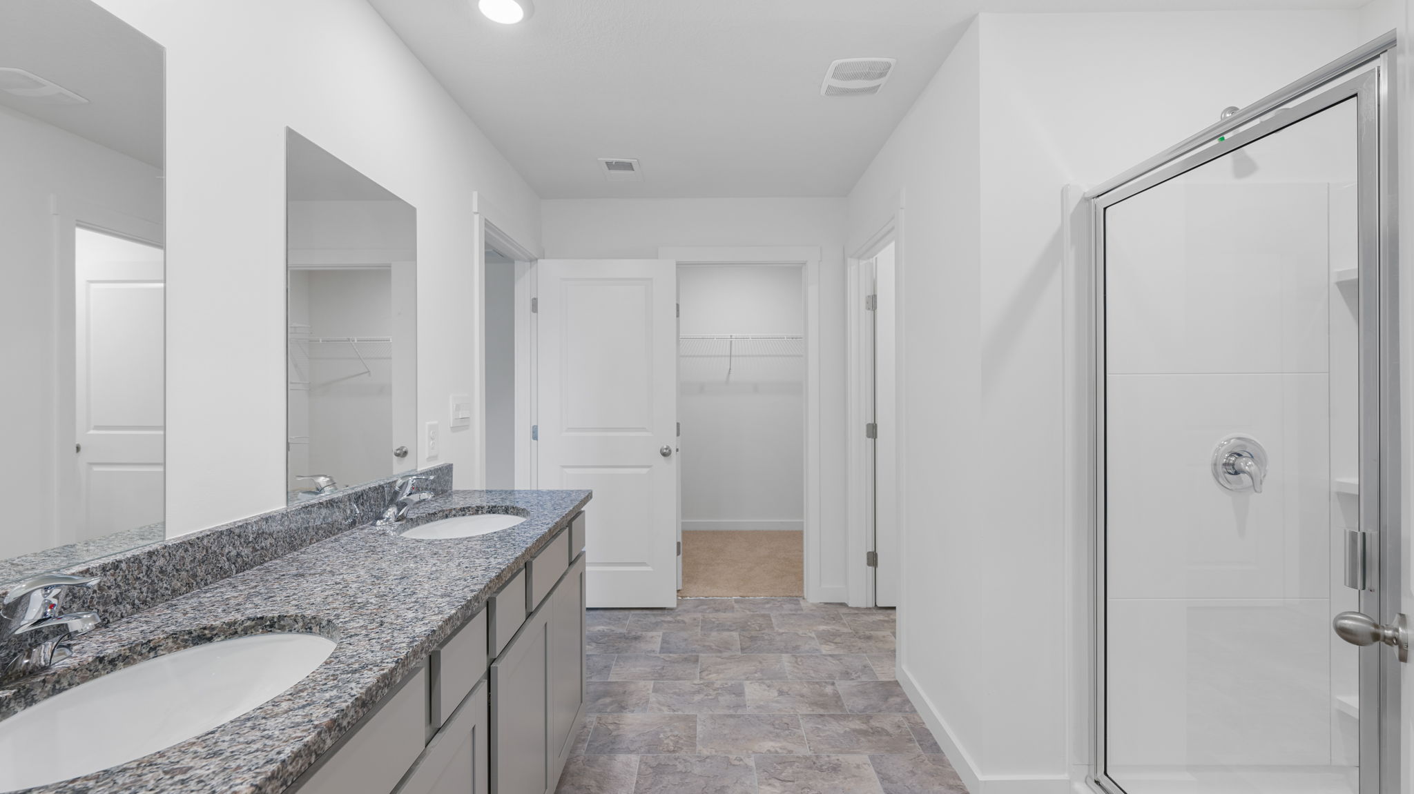 primary bathroom with double vanity and walk-in shower