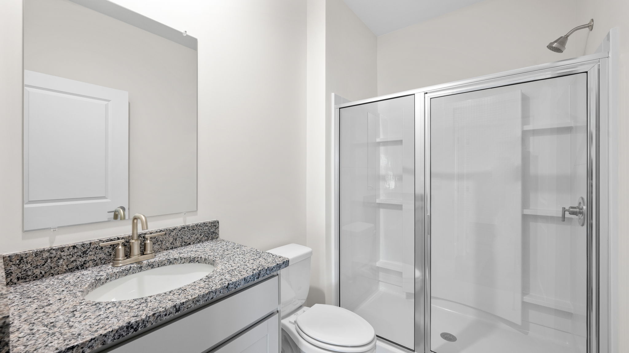 The bath has sink and shower with white cabinets.