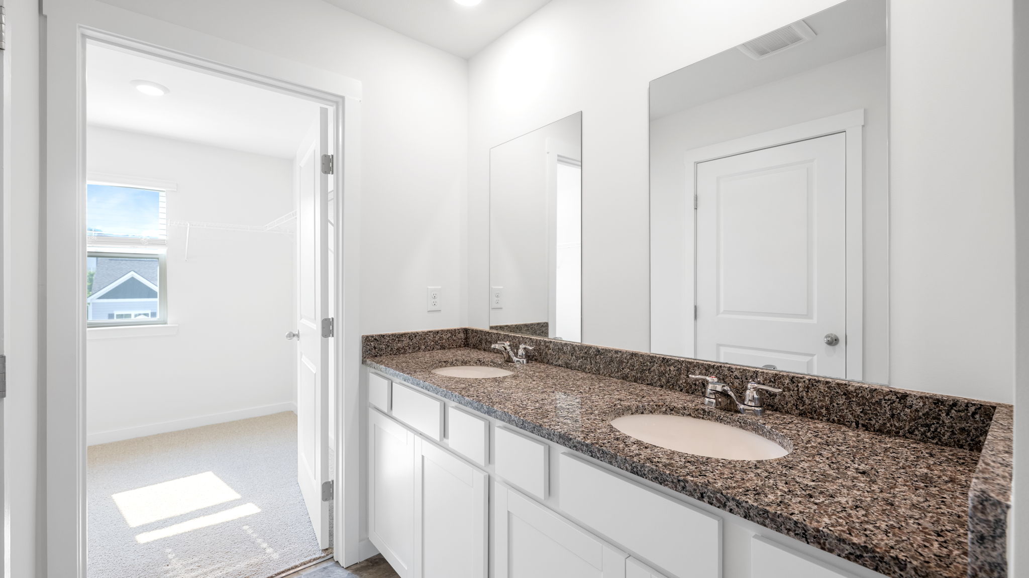 the ensuite bathroom has a vanity with cabinets and mirrors