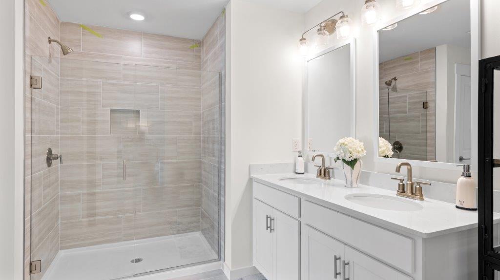 primary bathroom with double vanity and walk in shower