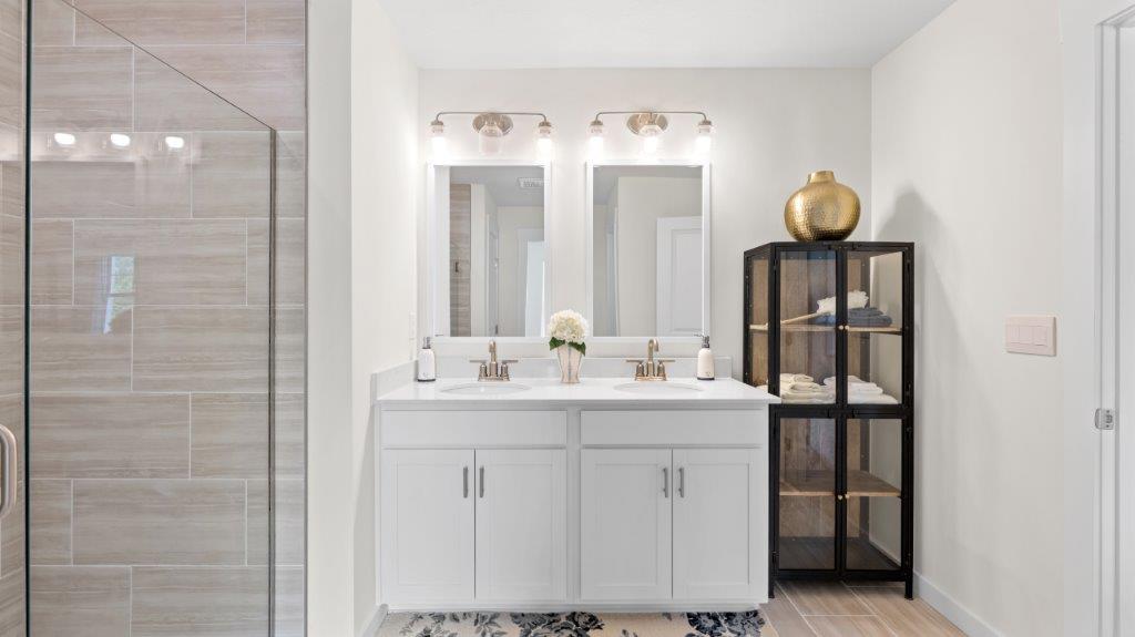 primary bathroom with double vanity and walk in shower