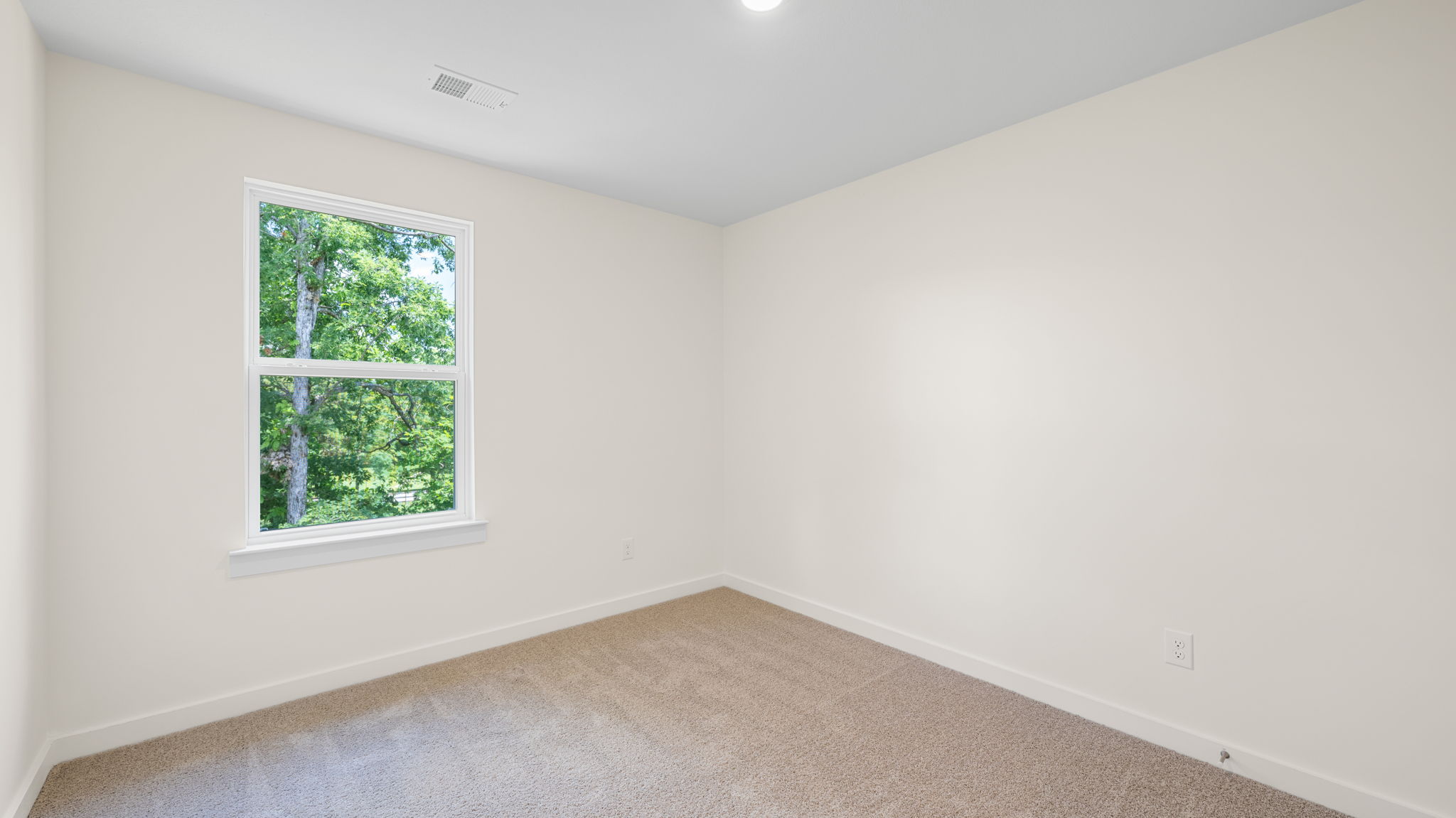 Bedroom with neutral walls, carpet, and a window.