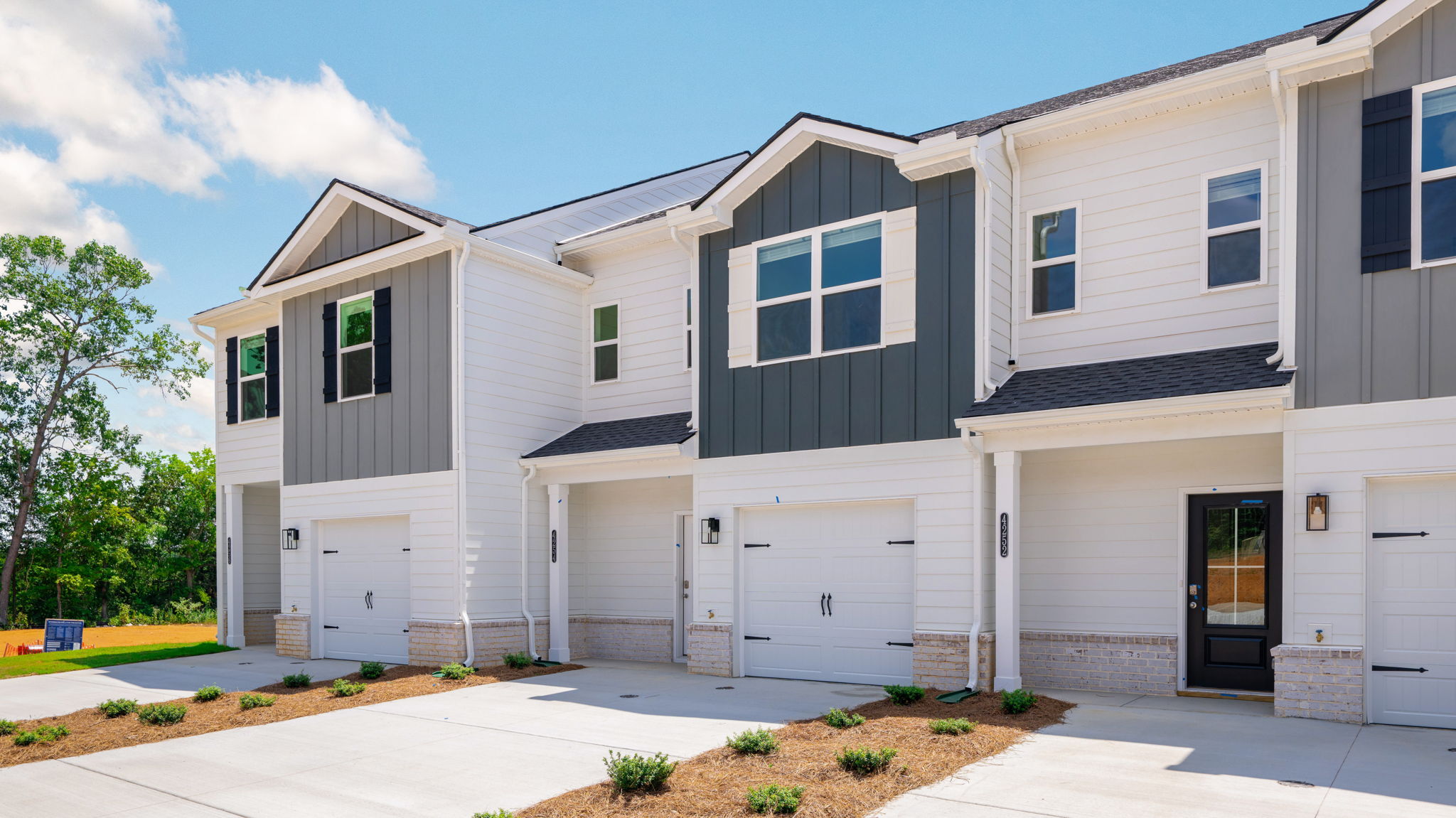 Two story home with neutral exterior and paved driveway.