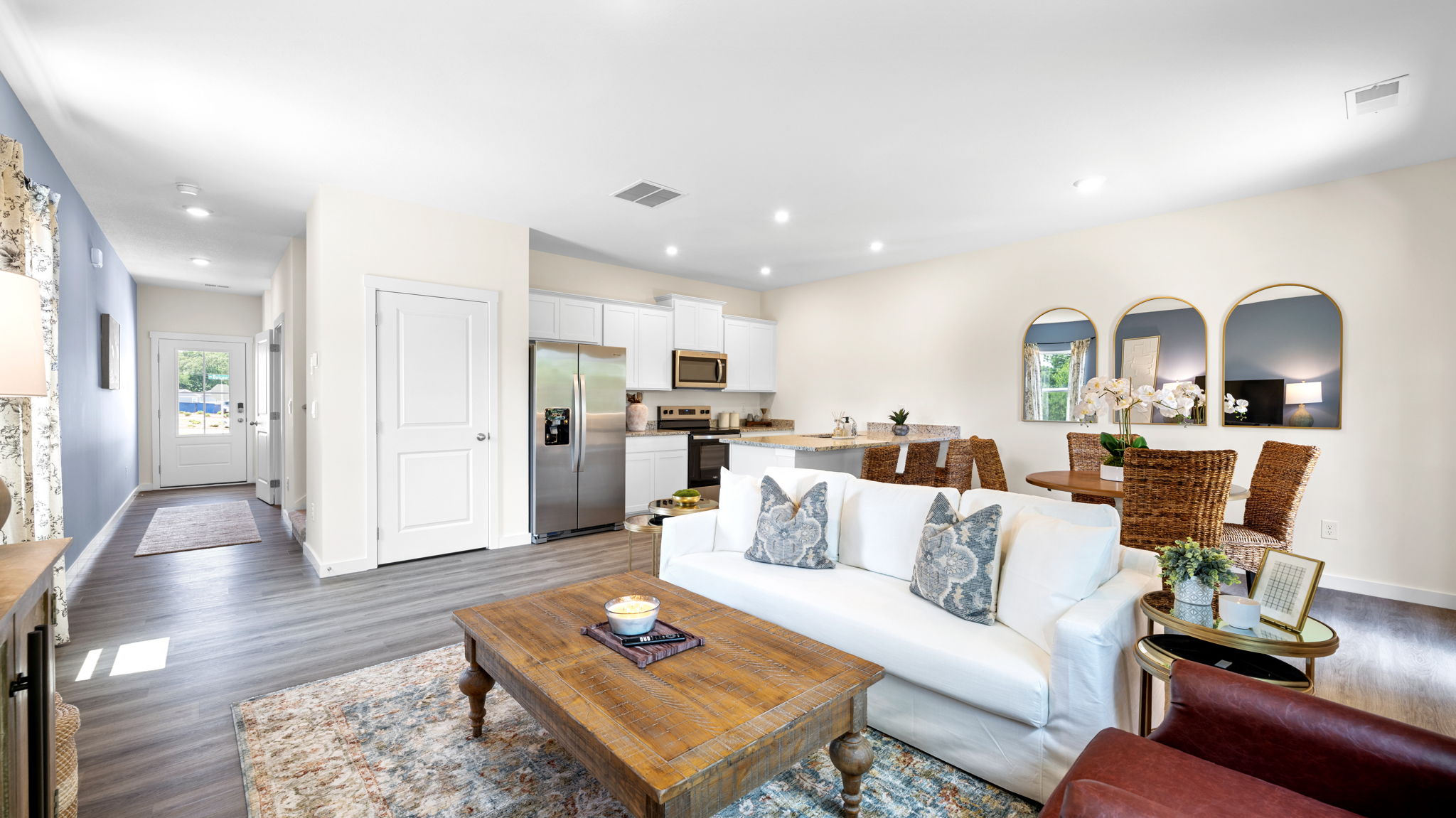 Main living area with clean flooring and natural light connecting to dining area.