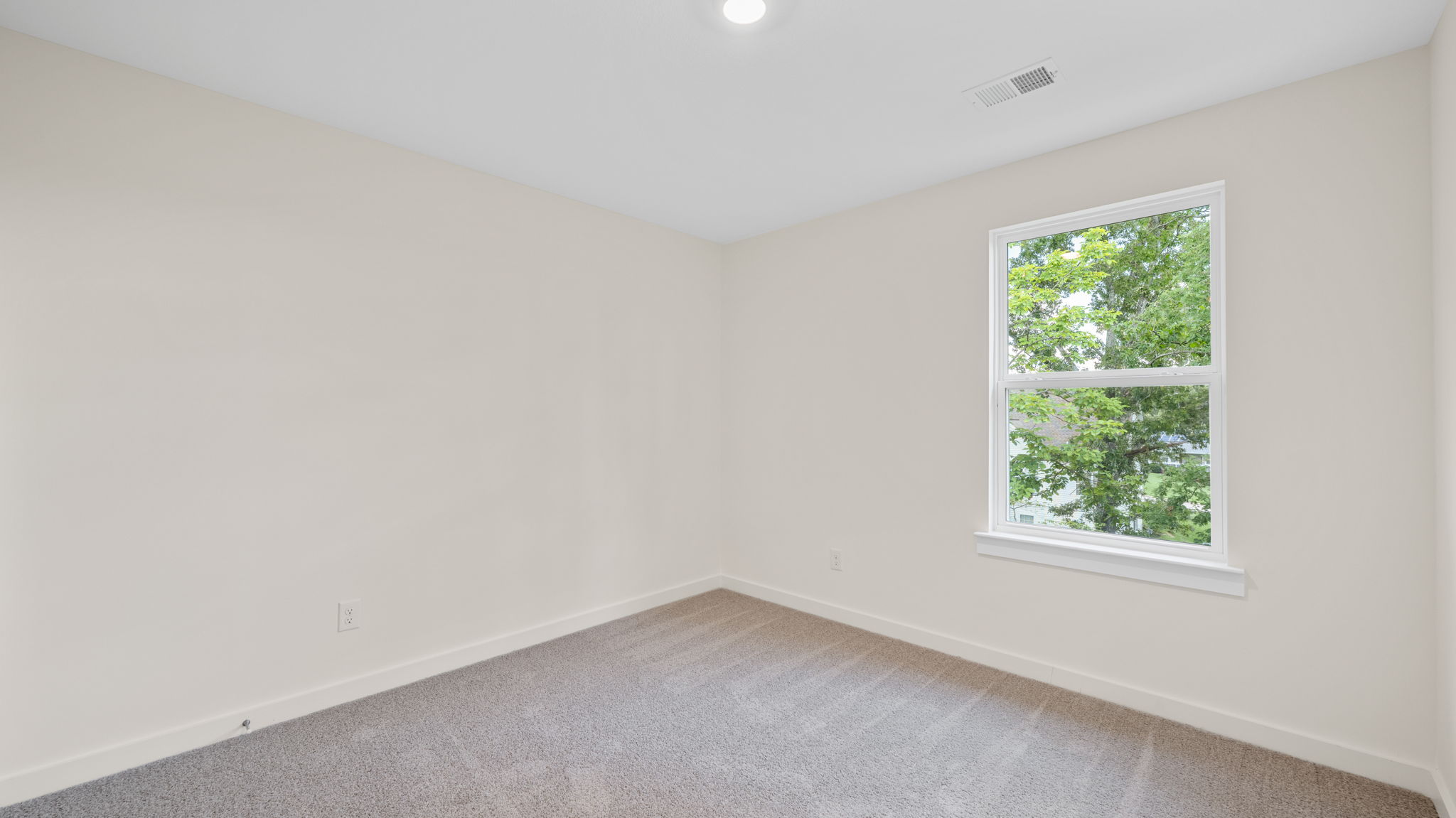 Bedroom with neutral walls, carpet, and a window.