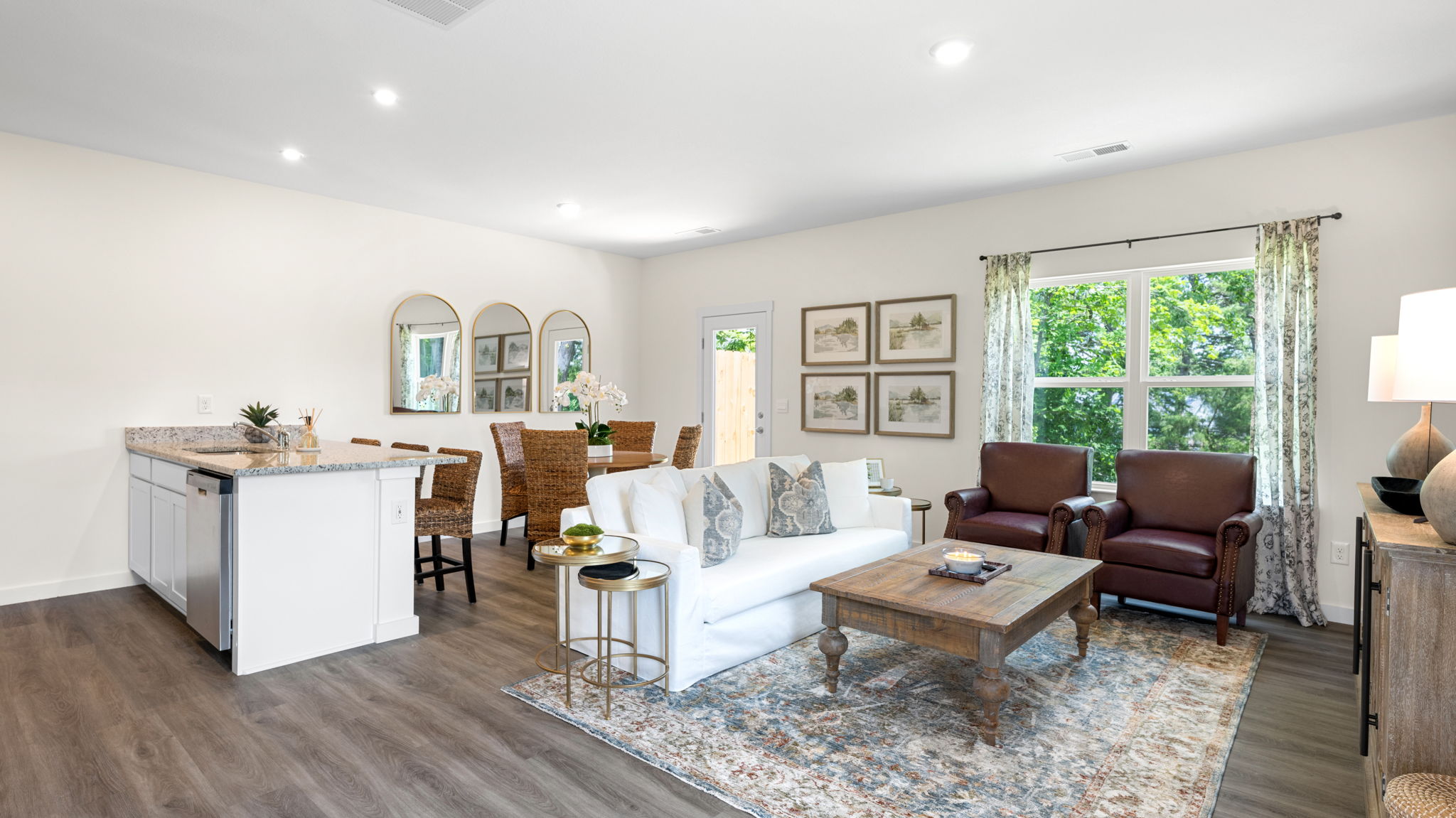Open concept living space with natural light and simple furnishings connecting to kitchen and dining space.