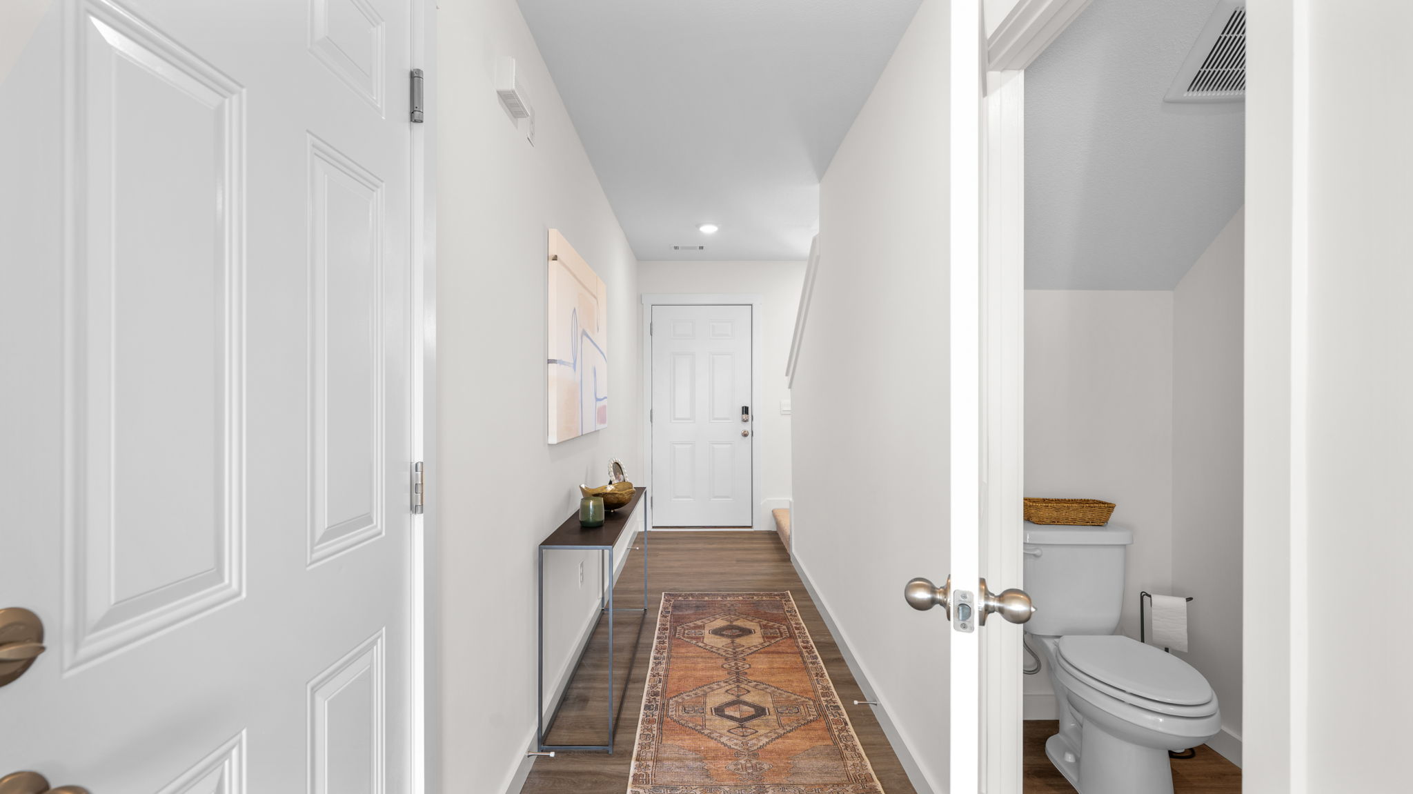 entryway hallway facing front door, half bathroom to the right