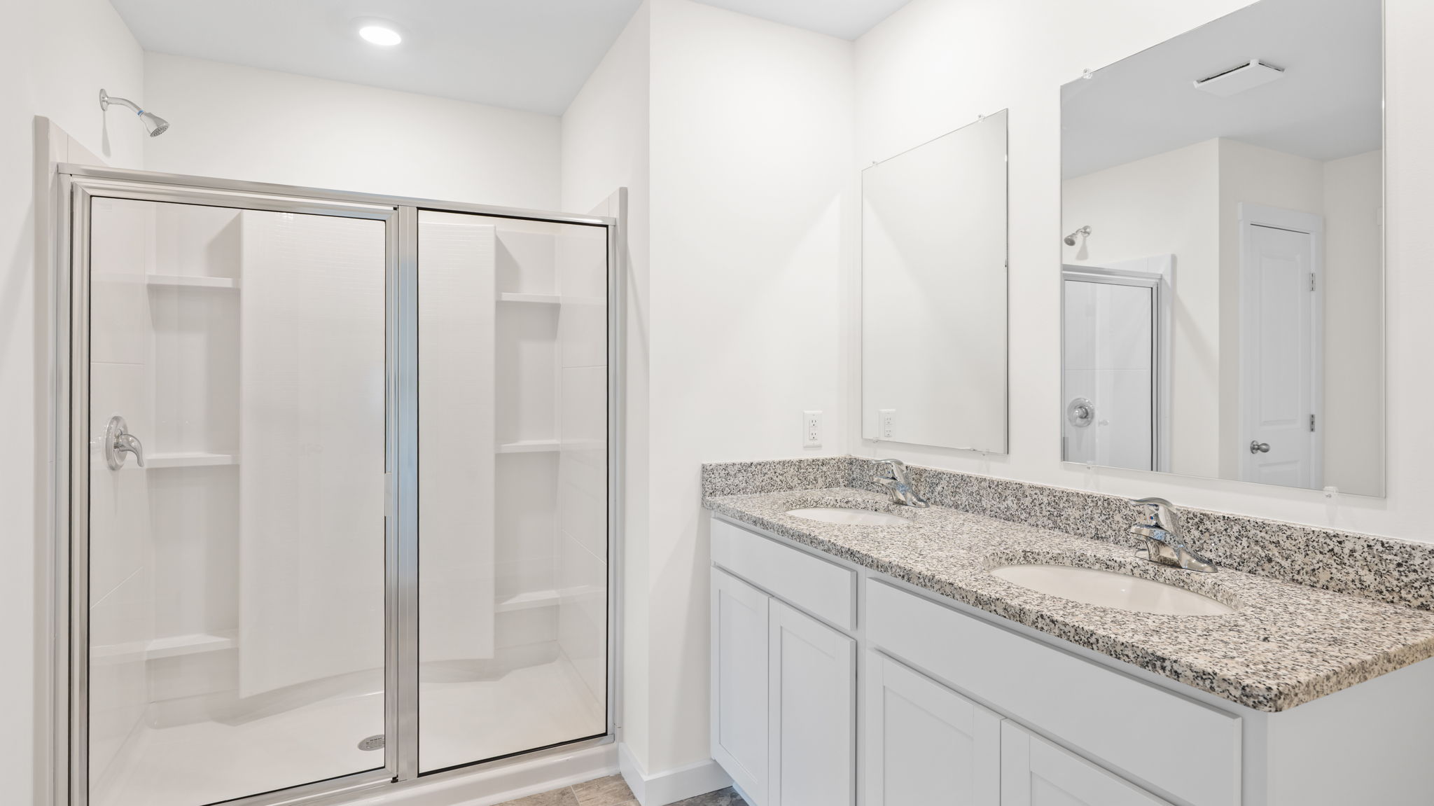 primary bathroom with long vanity with two sinks and a standing shower
