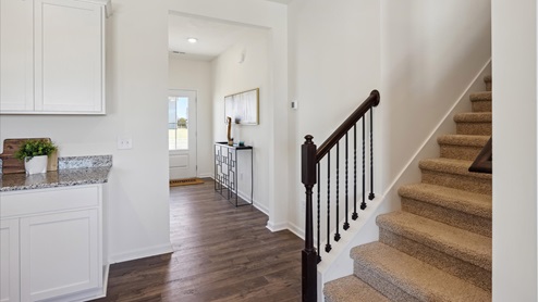 Entrance of home with revwood flooring and staircase to second level