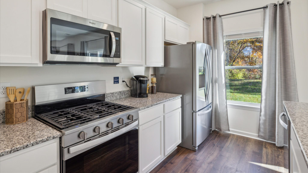 Kitchen with stainless steel appliances, shaker style cabinets, and elevated finishes