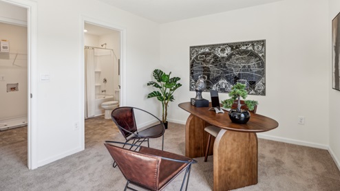 Bedroom with two accent chairs and desk with plant