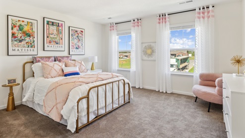 Bedroom with bed and pink bedspread with pink accent chair
