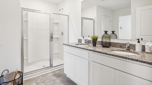 primary bathroom with double sinks and walk in shower