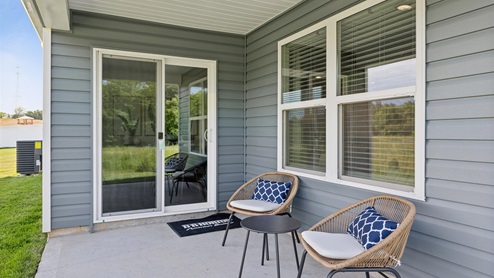 Back patio of home with sliding glass door and two chairs with a small outdoor table