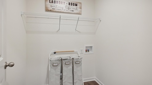 Laundry room with washer and dryer hookups and white wire shelving. There are cloth laundry baskets set up