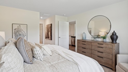 Primary bedroom with white bedding and wooden dresser