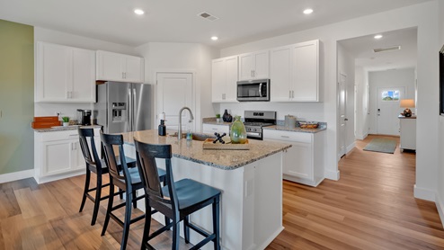 Spacious kitchen with white cabinetry, large island and stainless steel appliances