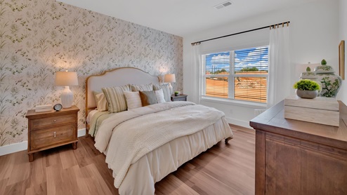 primary bedroom with a wall paper accent wall, white bed, and large window