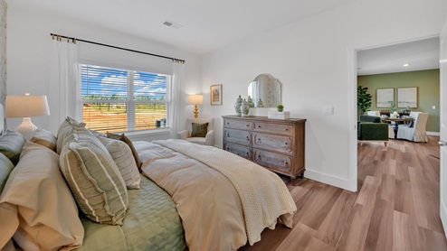 primary bedroom with a wall paper accent wall, white bed, and large window